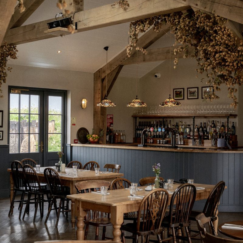 Restaurant interior with wooden tables, chairs, and a bar area.